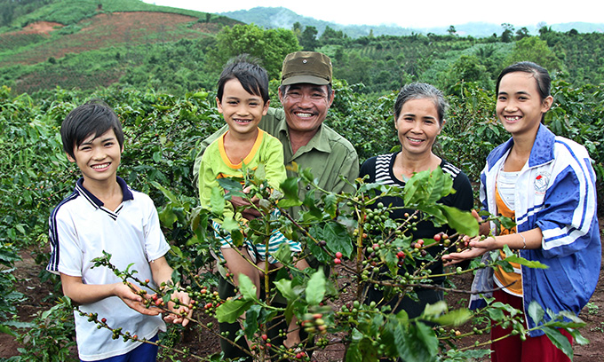 커피나무 앞에서 웃고 있는 민의 가족. 민의 아버지는 작년 월드비전 후엉호아 사업장에서 실시한 농업기술 역량강화 훈련에 참여해 커피생산량을 늘리는 기술을 배웠다.