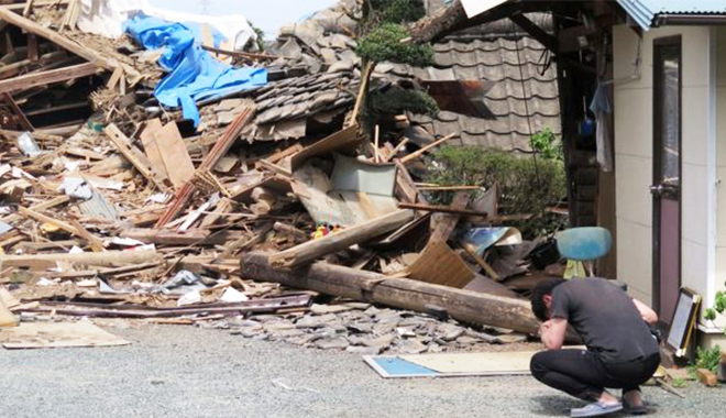 피해주민이 지진으로 인해 무너진 가옥 앞에서 좌절하고 있다(사진출처:BBC)